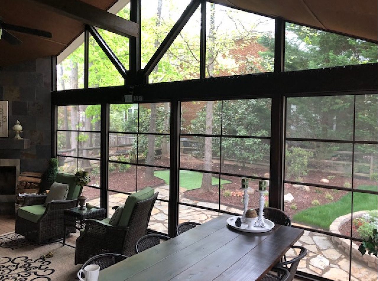 Black-framed three-season room with a dining table