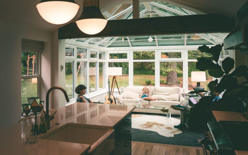 Bright interior of a custom sunroom with a peaked glass roof, pendant lights and a kitchen living space, built by Serene Sunrooms in Vaughan, Ontario