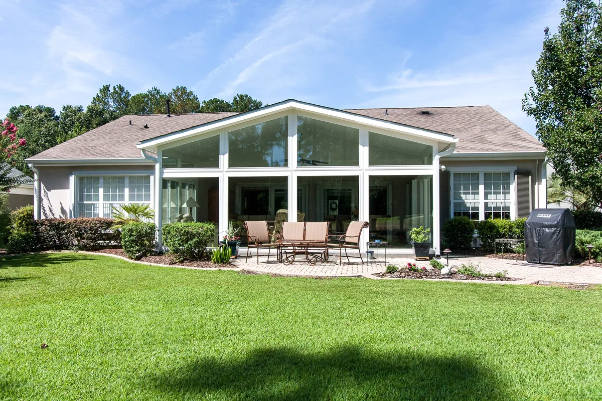 Wide cathedral-roof sunroom across the back of a bungalow, facing the lawn