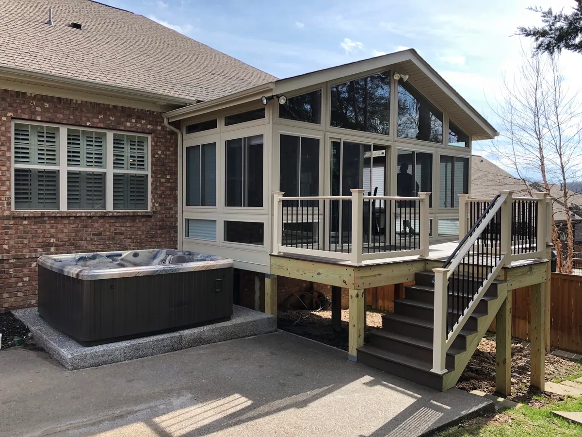 Gable-roof sunroom raised on a deck, with stairs down to a hot tub terrace