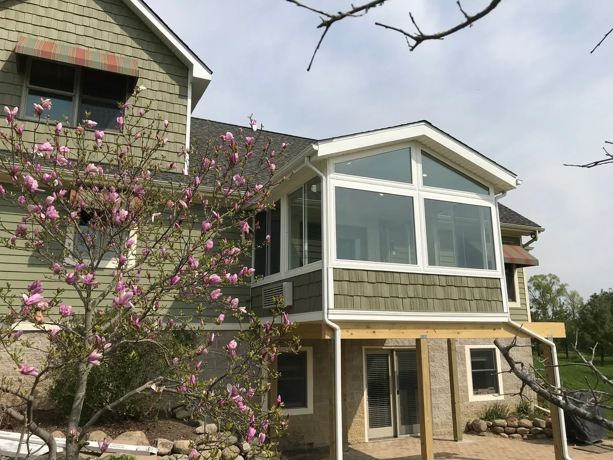 Raised gable sunroom on a two-storey home among spring blossom