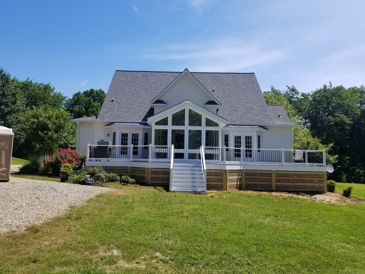 A-frame-roof sunroom on a raised deck with stairs to the lawn