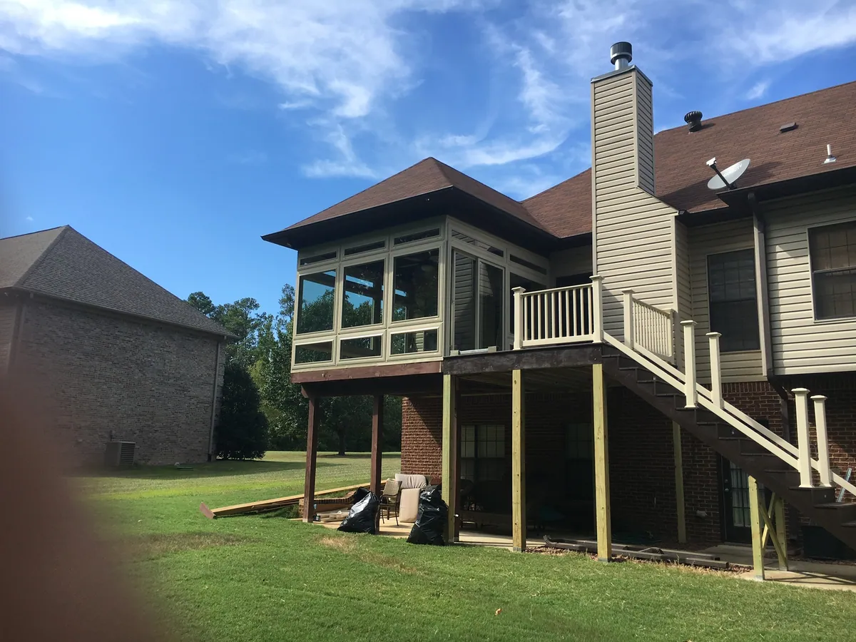 Raised dark-framed sunroom on posts with a stair to the garden