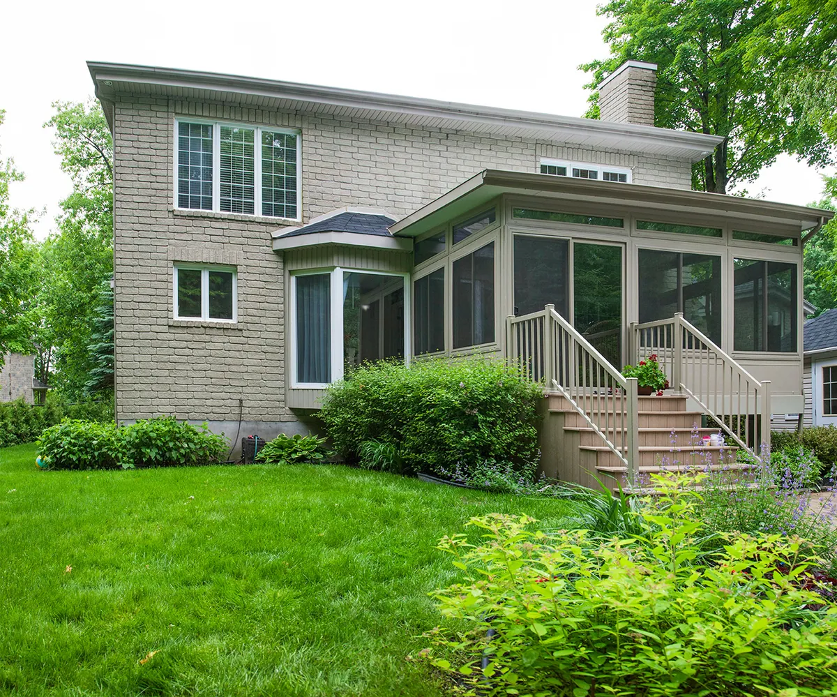 Bay-front sunroom with stairs stepping down into a planted garden
