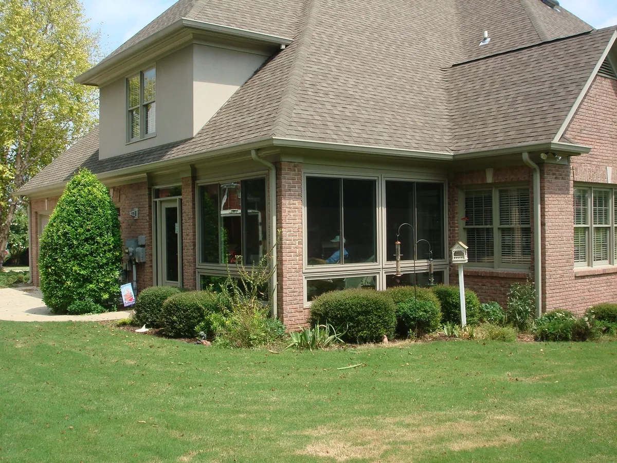 Sunroom spanning the rear of a brick home, framed in warm brown