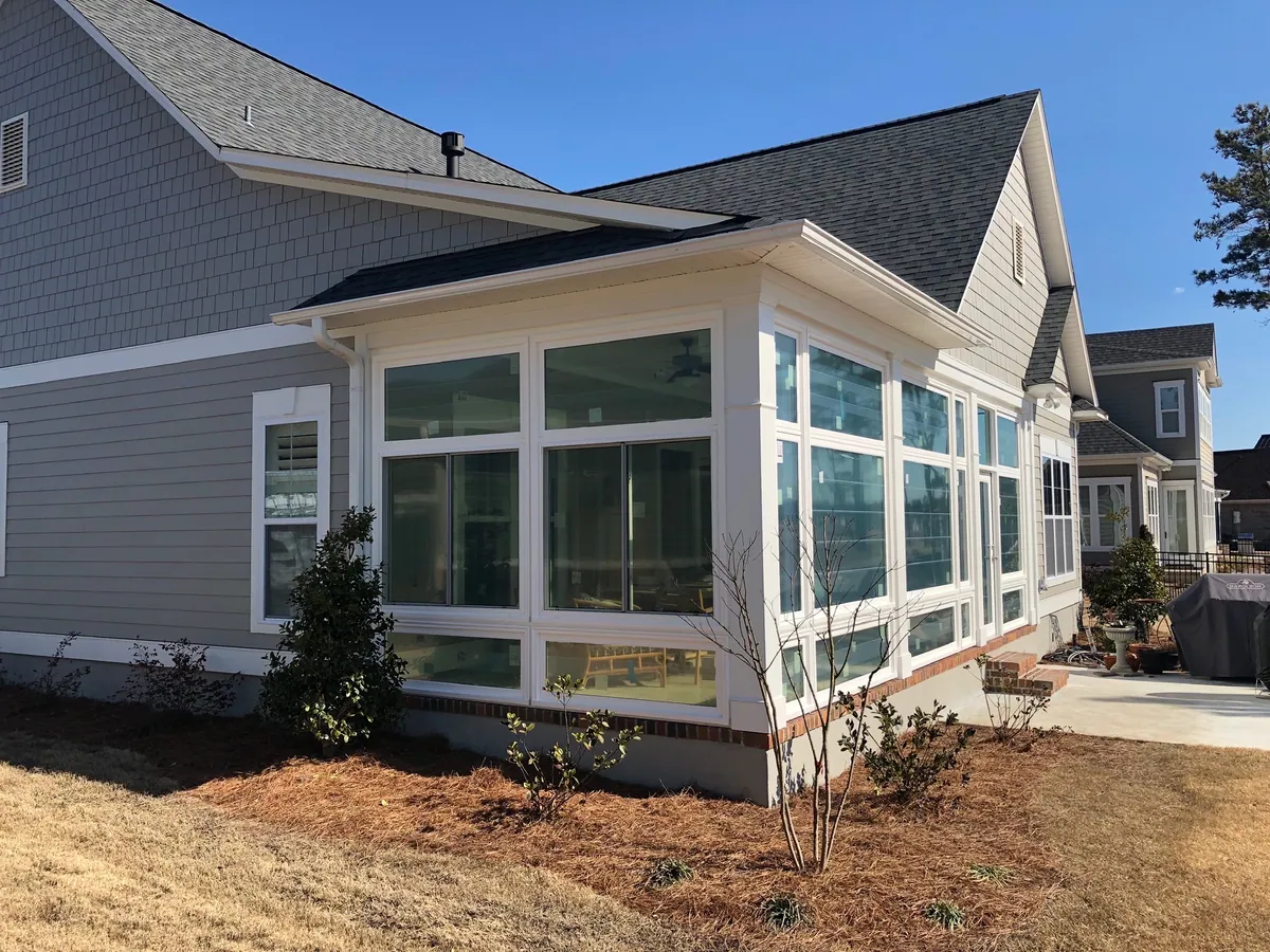 White multi-pane sunroom on a grey-sided home
