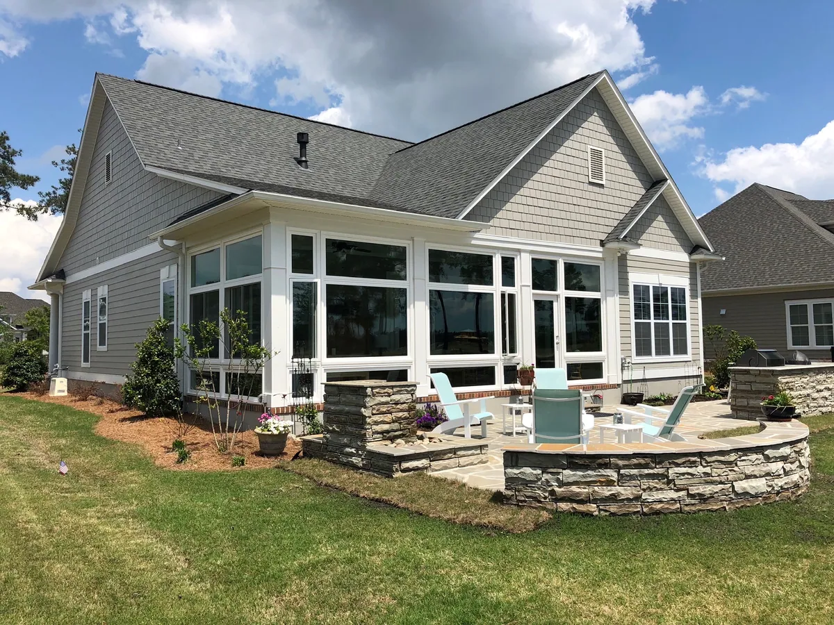 White sunroom opening onto a curved stone patio