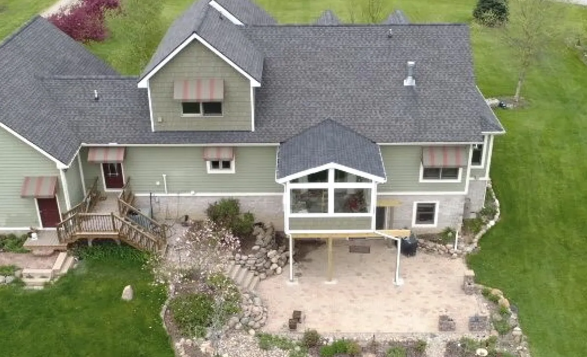 Aerial view of a gable sunroom and patio behind the house