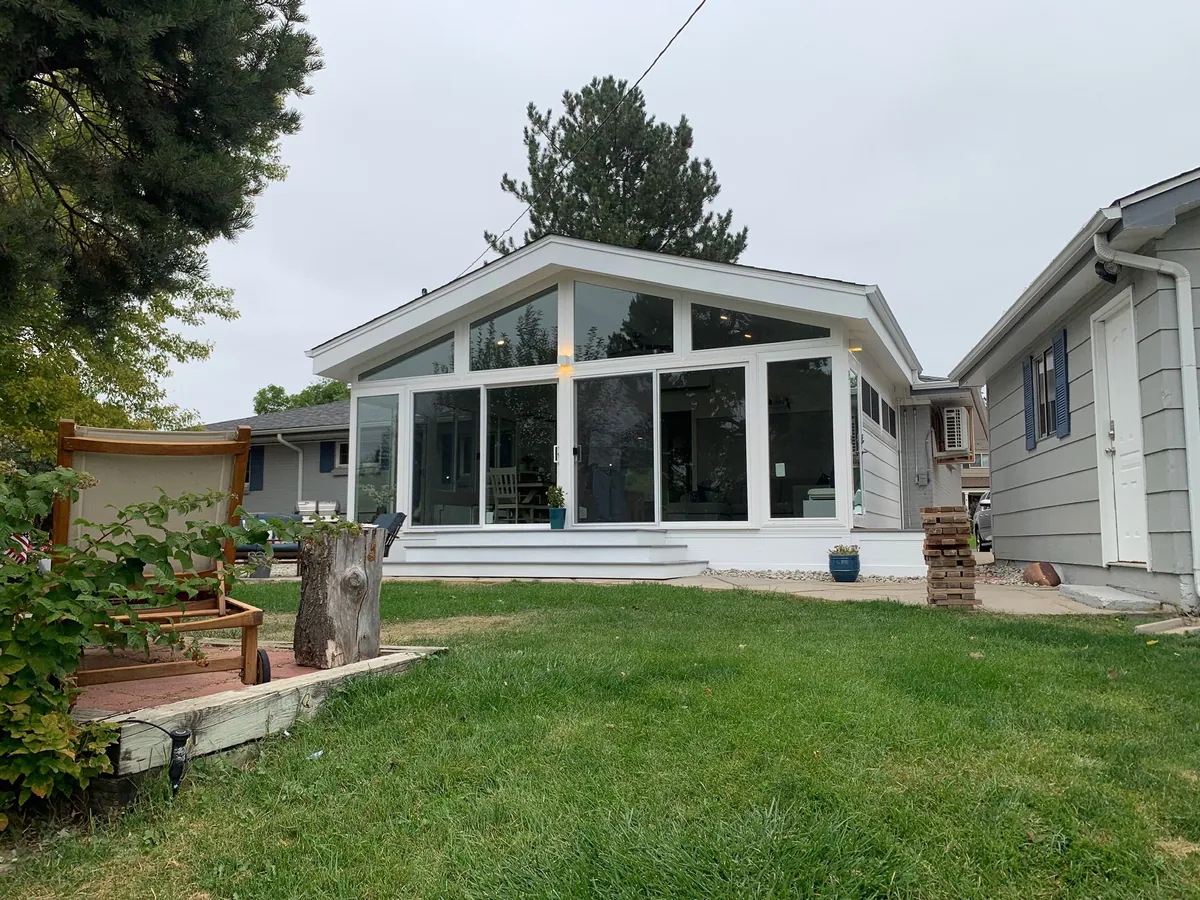 White gable sunroom opening onto a green lawn