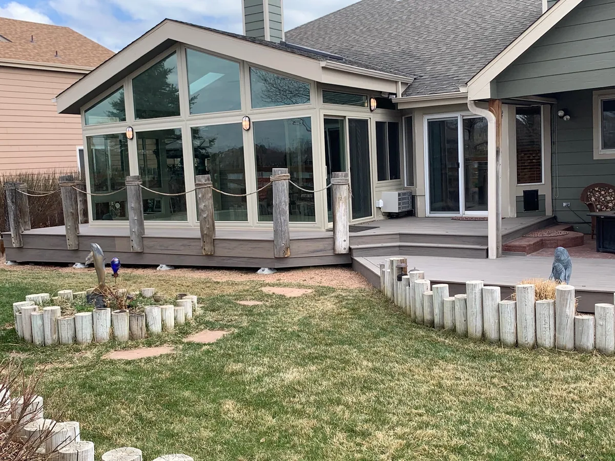 Sunroom with a timber-edged deck and lawn