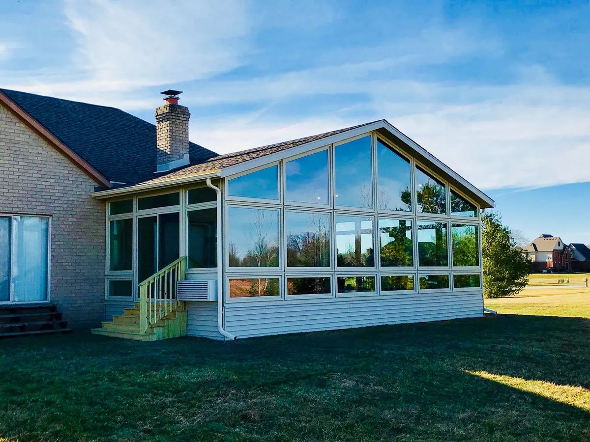 Gable sunroom on a stone-and-siding home at the edge of a field