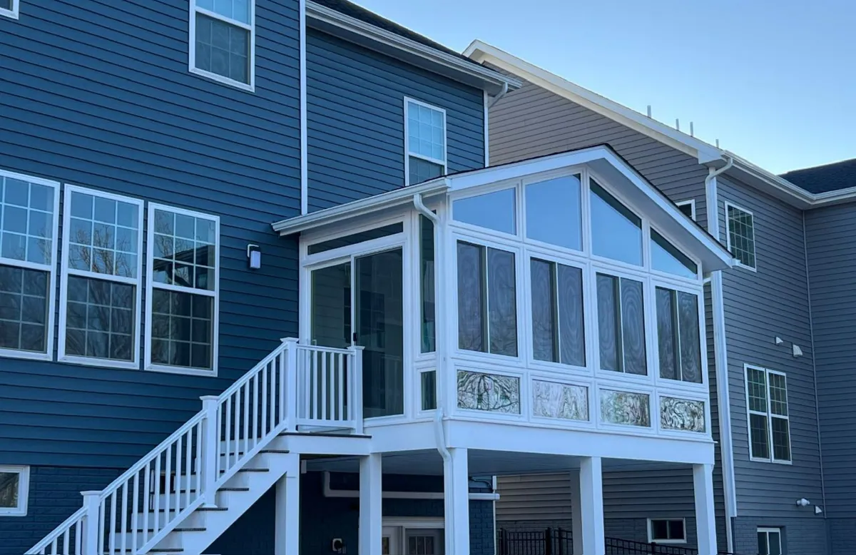 Raised white sunroom with a stair on a blue two-storey home