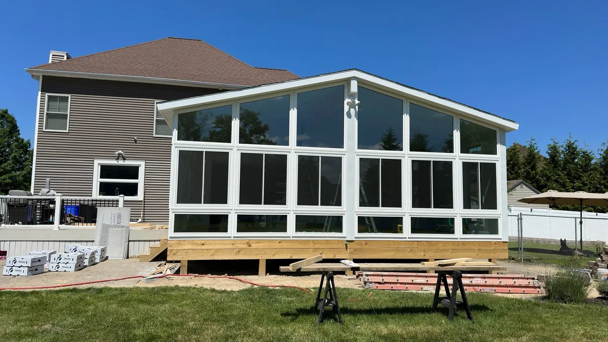 White gable sunroom and deck behind a two-storey home