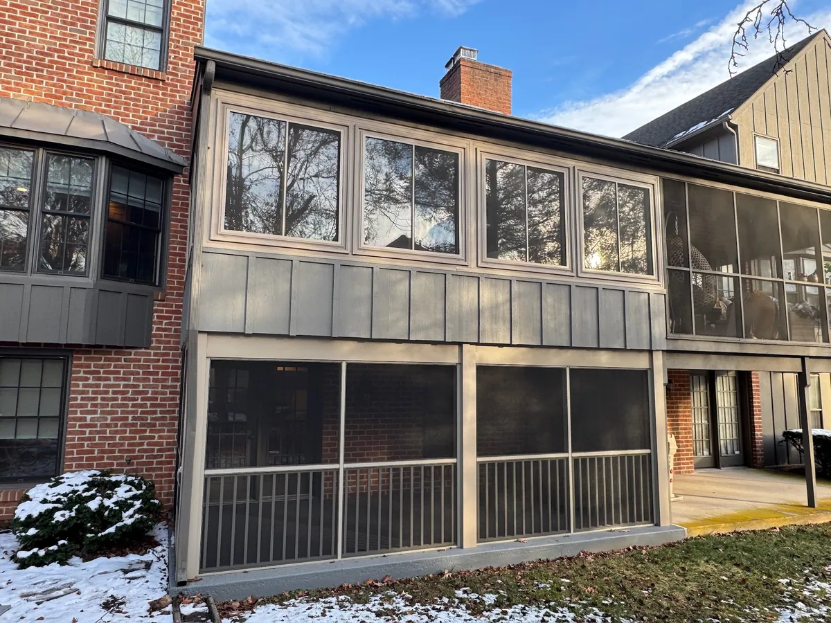 Stacked screened porches on a brick home, seen from the garden