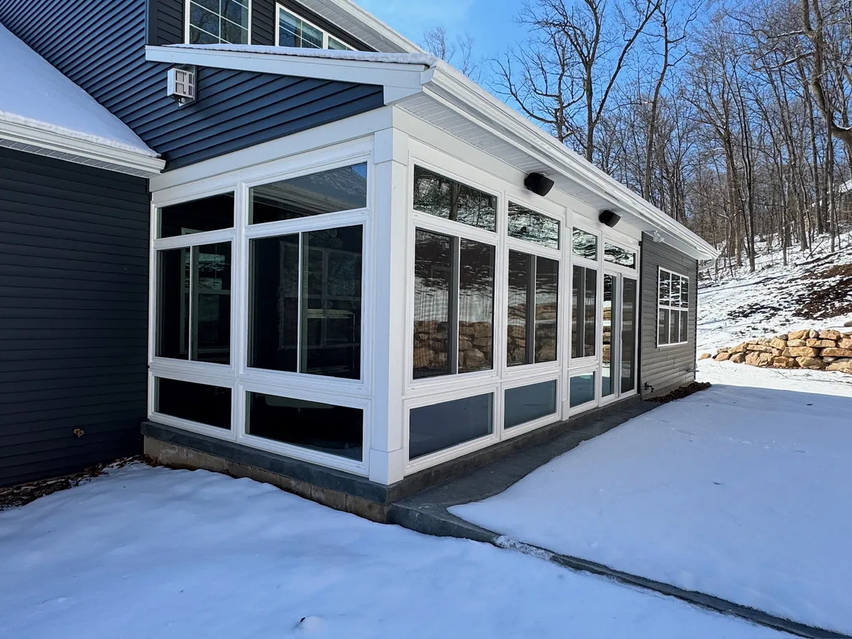 Sunroom wrapping the corner of a grey-sided home in winter