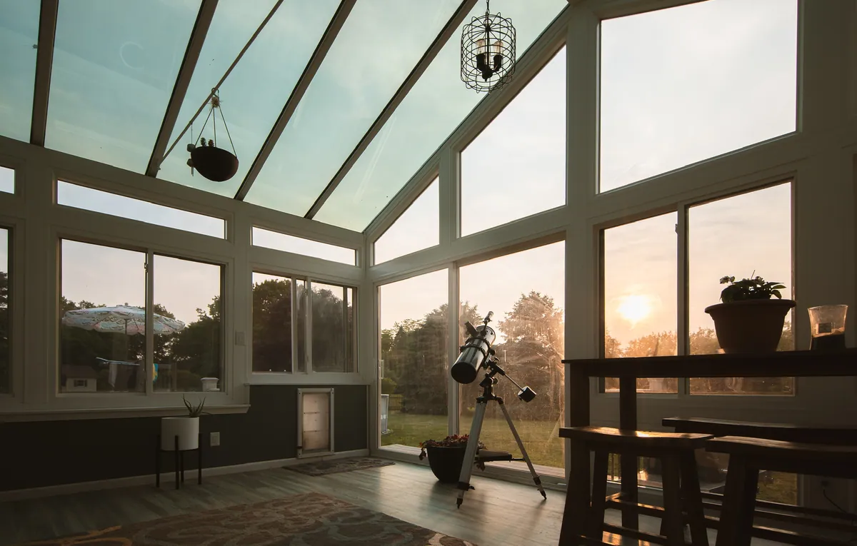 Glass-roof sunroom at sunset with a ceiling fan overhead