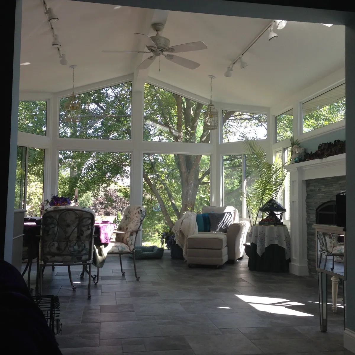 Sunroom lounge with a stone fireplace and garden views