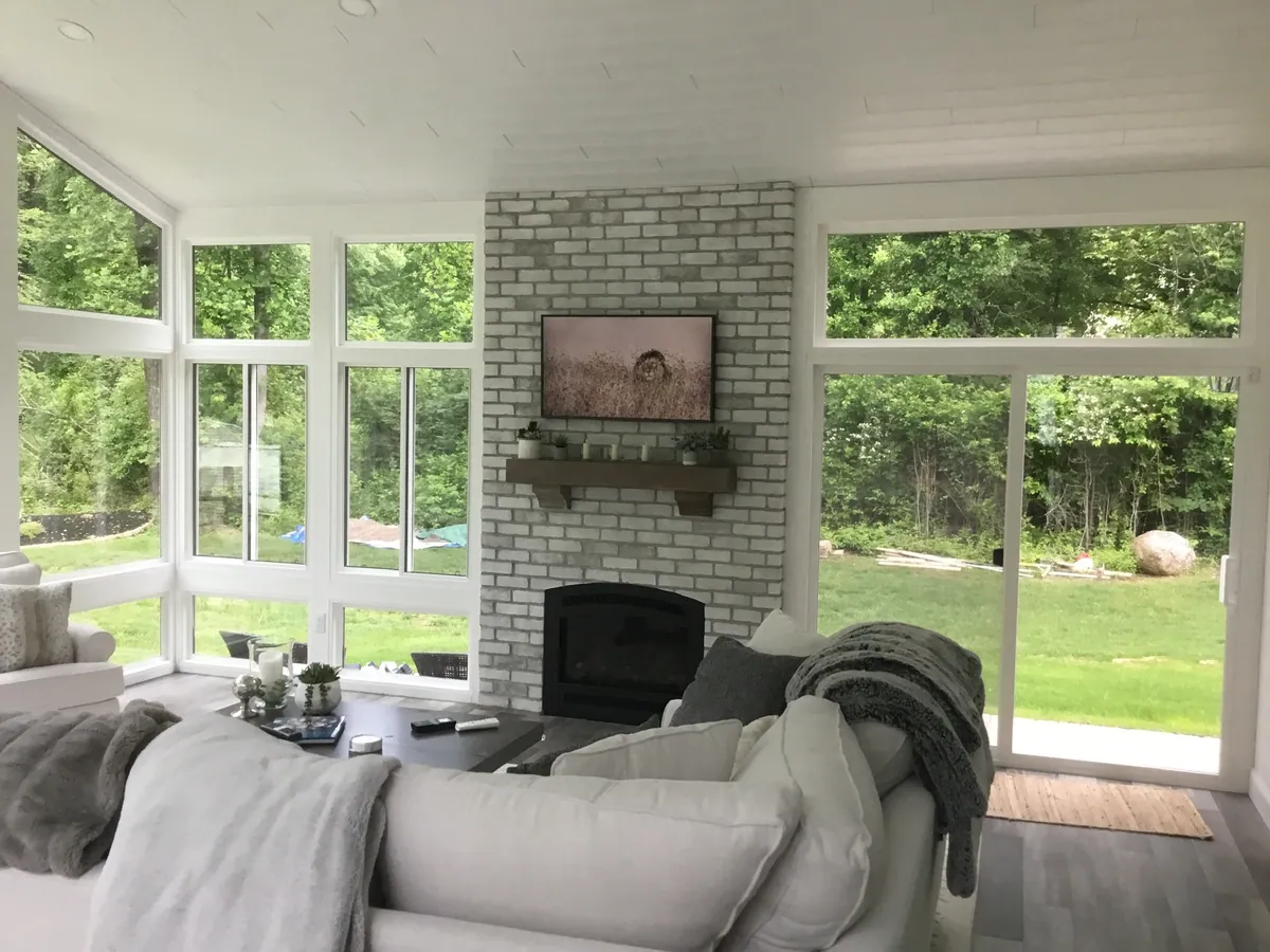Sunroom with a white brick fireplace and garden views