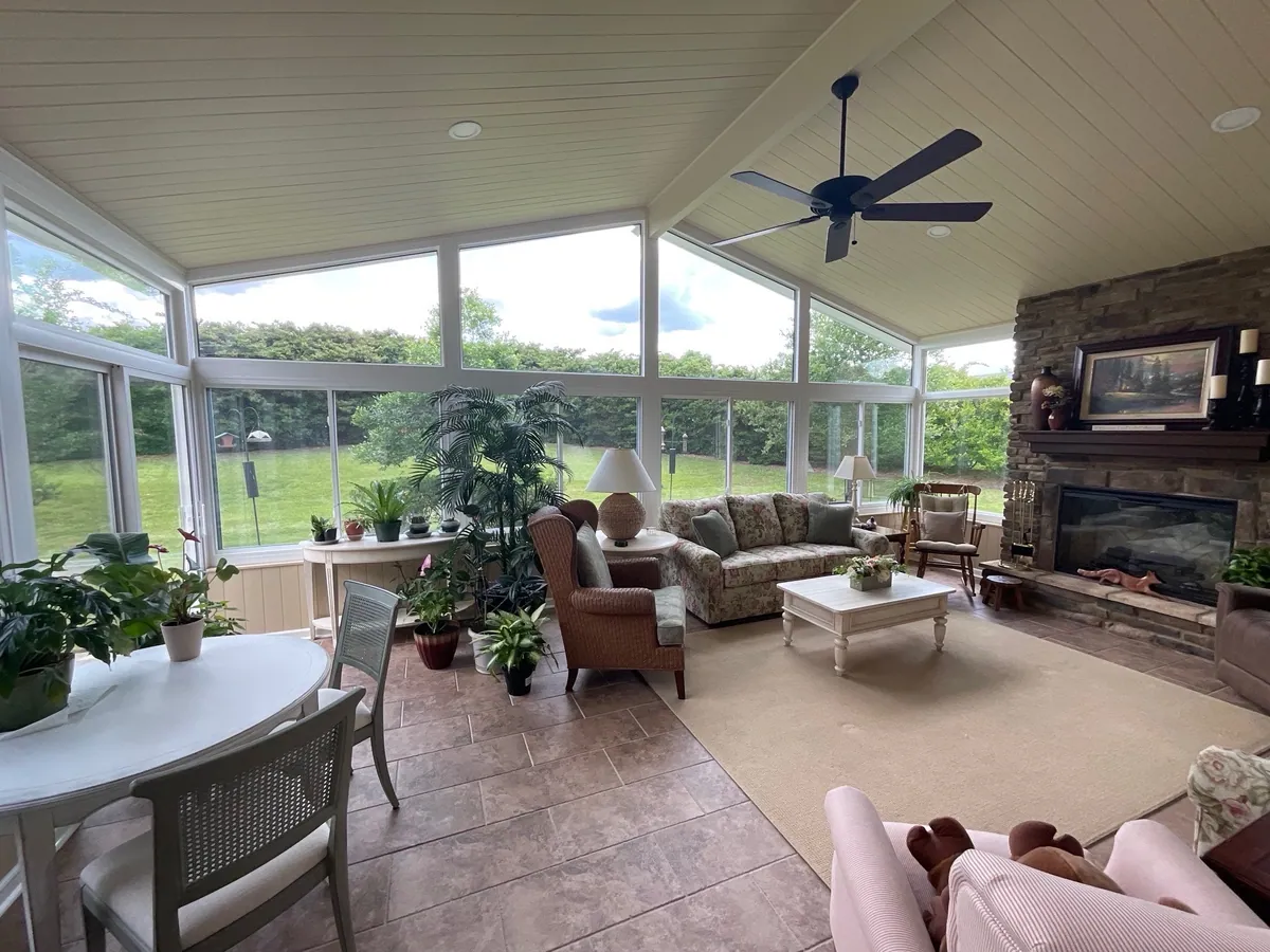 Sunroom with dining and seating areas under a ceiling fan