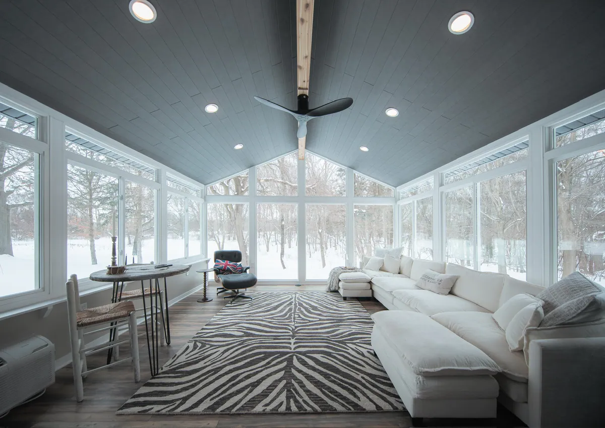 Grey-ceiling sunroom with a white sofa and snowy view