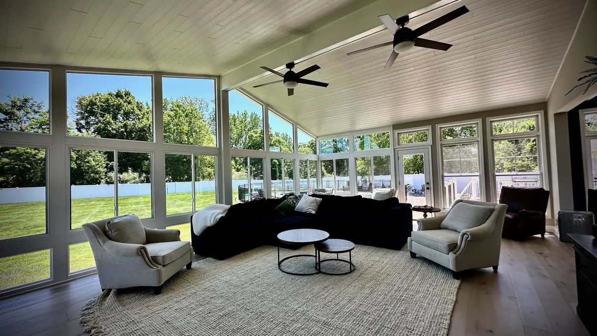 Sunroom with a white ceiling, dark sofa and large rug