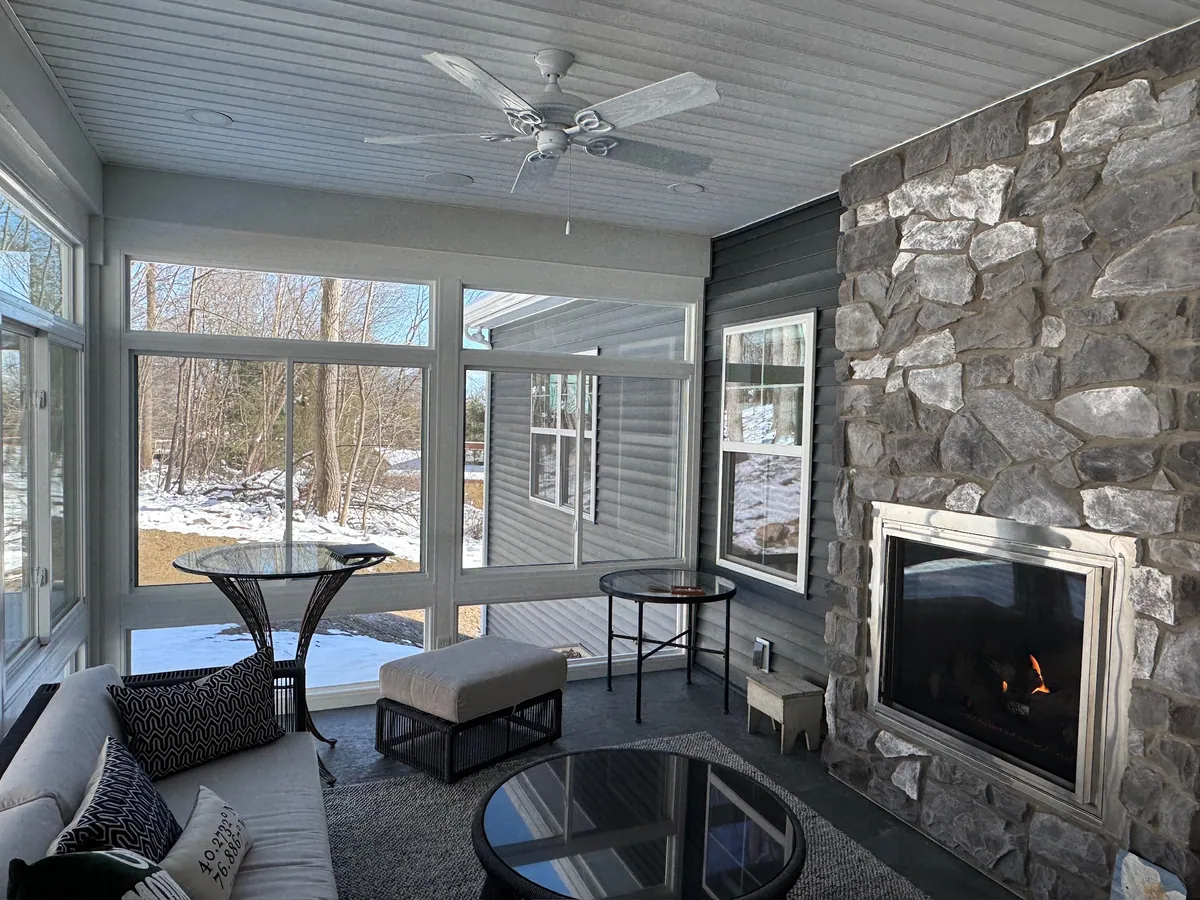 Stone fireplace wall inside a sunroom overlooking the snow